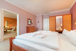 A hotel room with a large bed, a wardrobe, a mirror, and a door leading to another room. - Strandrose in the Villa Glückspilz (Binz)