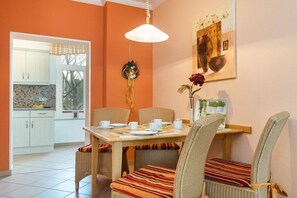 A dining area with a table set for four, surrounded by wicker chairs with striped cushions. - Strandrose in the Villa Glückspilz (Binz)