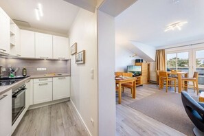 Une cuisine moderne avec des meubles blancs et un coin repas comprenant une table et des chaises en bois.