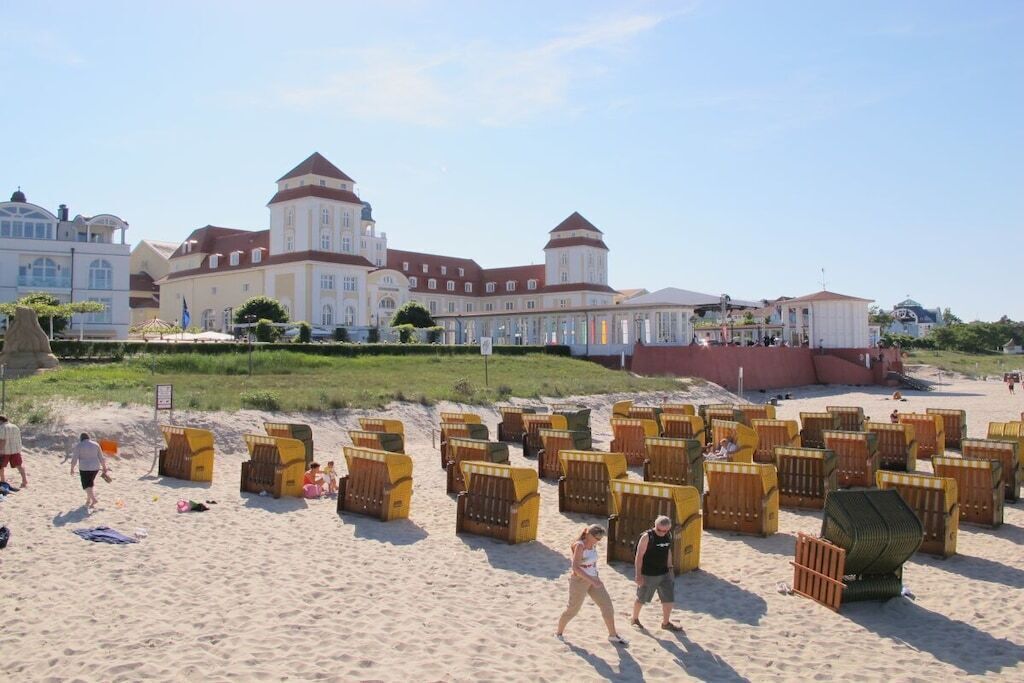 Ein Strand mit vielen Liegestühlen und ein großes Gebäude mit mehreren Türmen im Hintergrund.