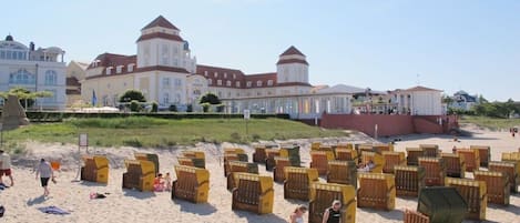 Ein Strand mit vielen Liegestühlen und ein großes Gebäude mit mehreren Türmen im Hintergrund.