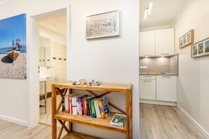A modern interior with a wooden bookshelf, a framed painting, and a kitchen area. - Seaside joy at the Baltic Sea House (Binz)
