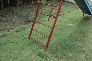 Una escalera metálica roja apoyada sobre césped.