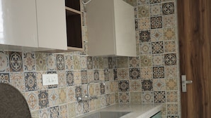 Una cocina con baldosas estampadas, un lavamanos y armarios color turquesa.