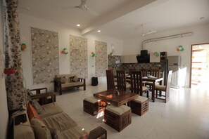 A spacious living area with a sofa, wooden coffee table, and dining set.