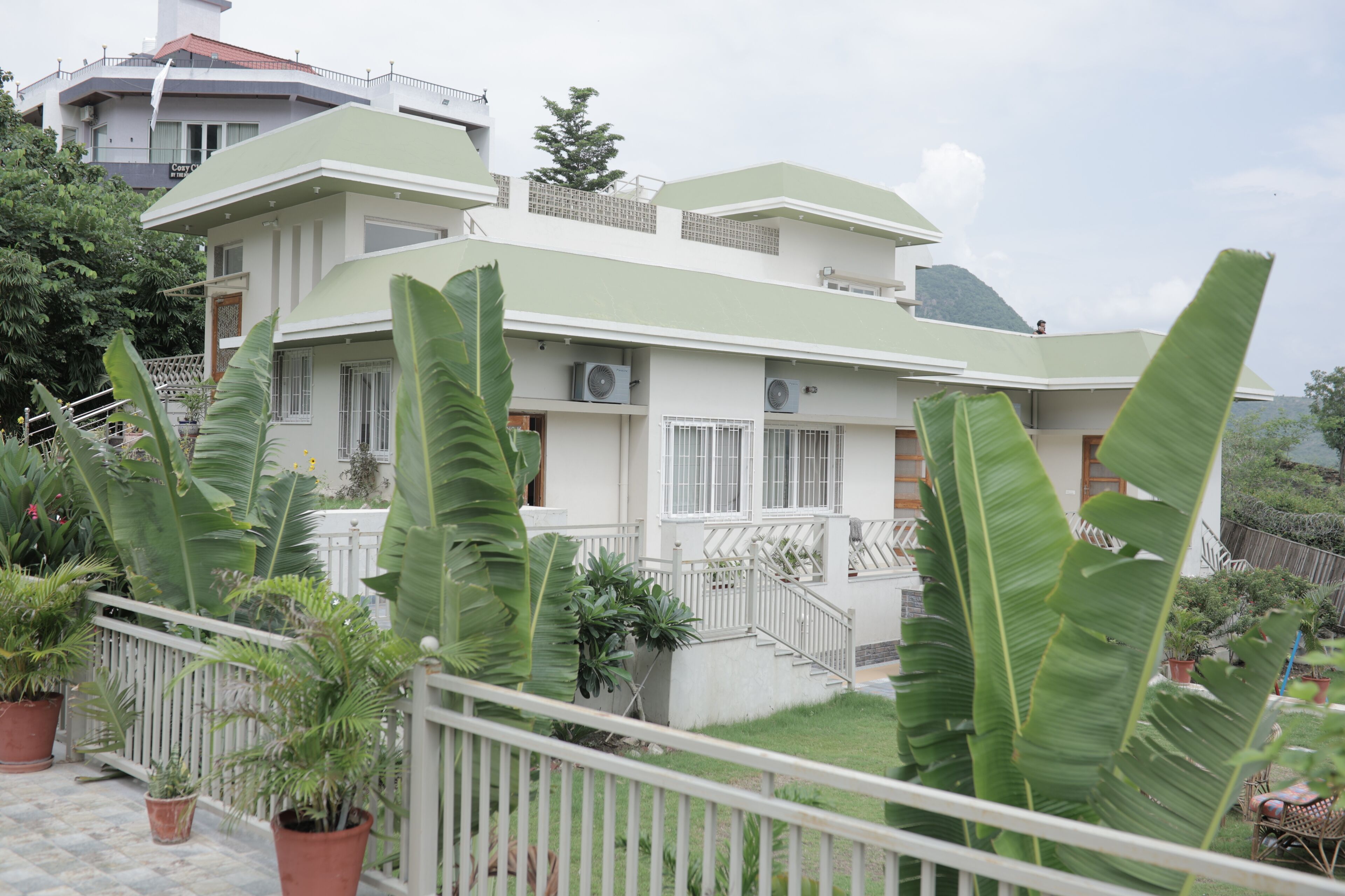 Un edificio residencial de varios pisos con un balcón, plantas en macetas y una escalera.