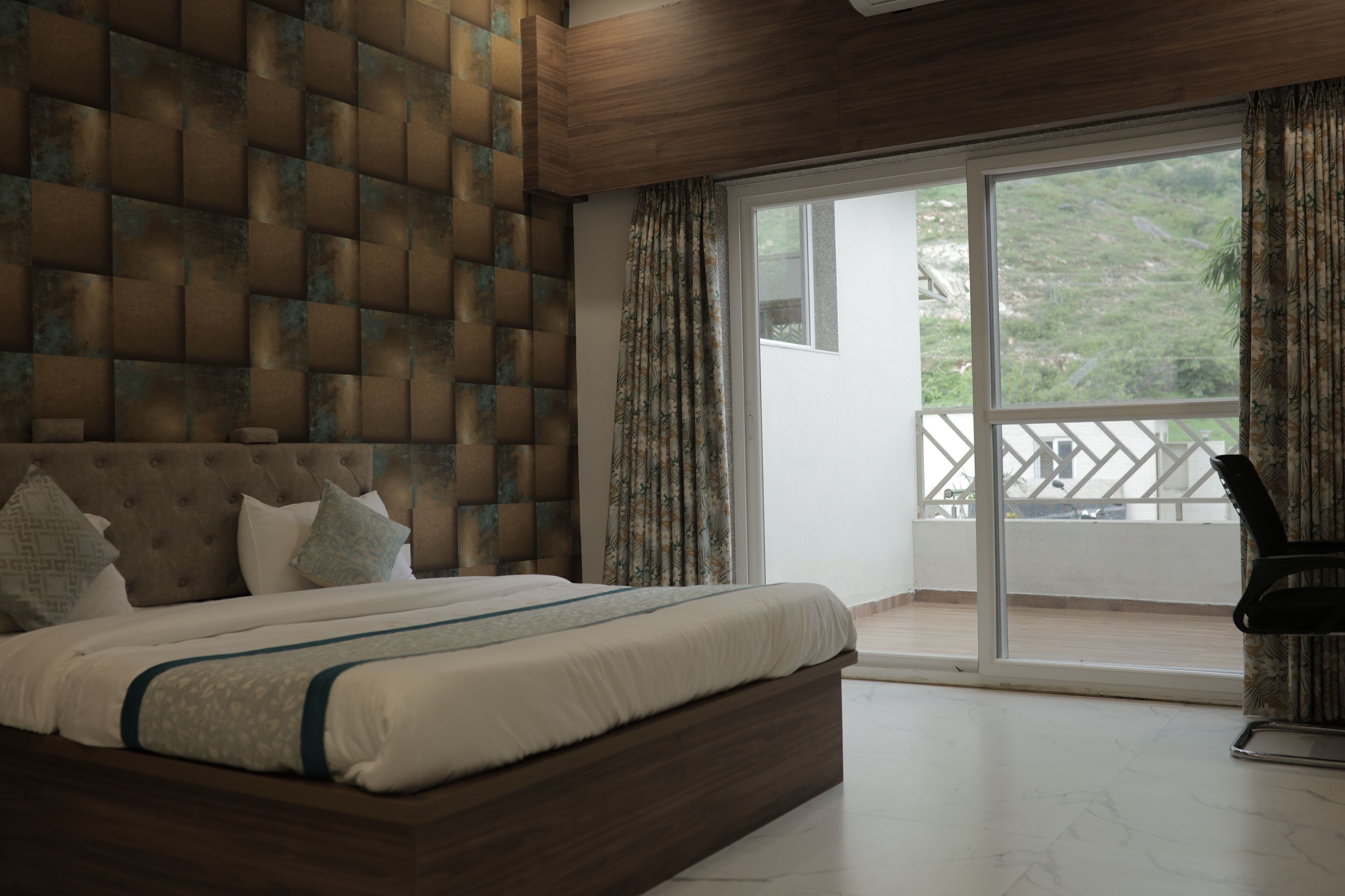 A bedroom with a large bed, a wooden headboard, and a view of the outdoors through a sliding glass door.