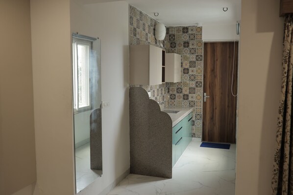A narrow hallway with a mirror, a sink, and a door leading to a bathroom.