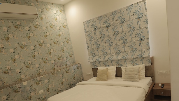 Un dormitorio moderno con una cama, una mesita de noche, un aire acondicionado instalado en la pared y un ventilador de techo.