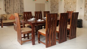 Uma sala de jantar com mesa e cadeiras de madeira, um sofá e papel de parede floral.