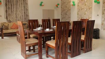 Uma sala de jantar com mesa e cadeiras de madeira, um sofá e papel de parede floral.