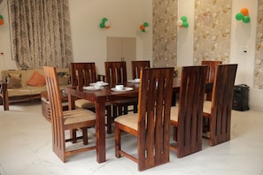 Uma sala de jantar com mesa e cadeiras de madeira, um sofá e papel de parede floral.