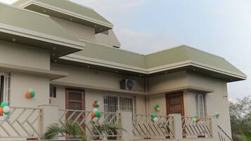 A two-story building with a flat roof and a balcony.
