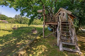 A rustic wooden structure with a staircase and a signpost, surrounded by a fenced area and greenery. - Holiday apartment with 2 bedrooms (Haide\/Ummanz)