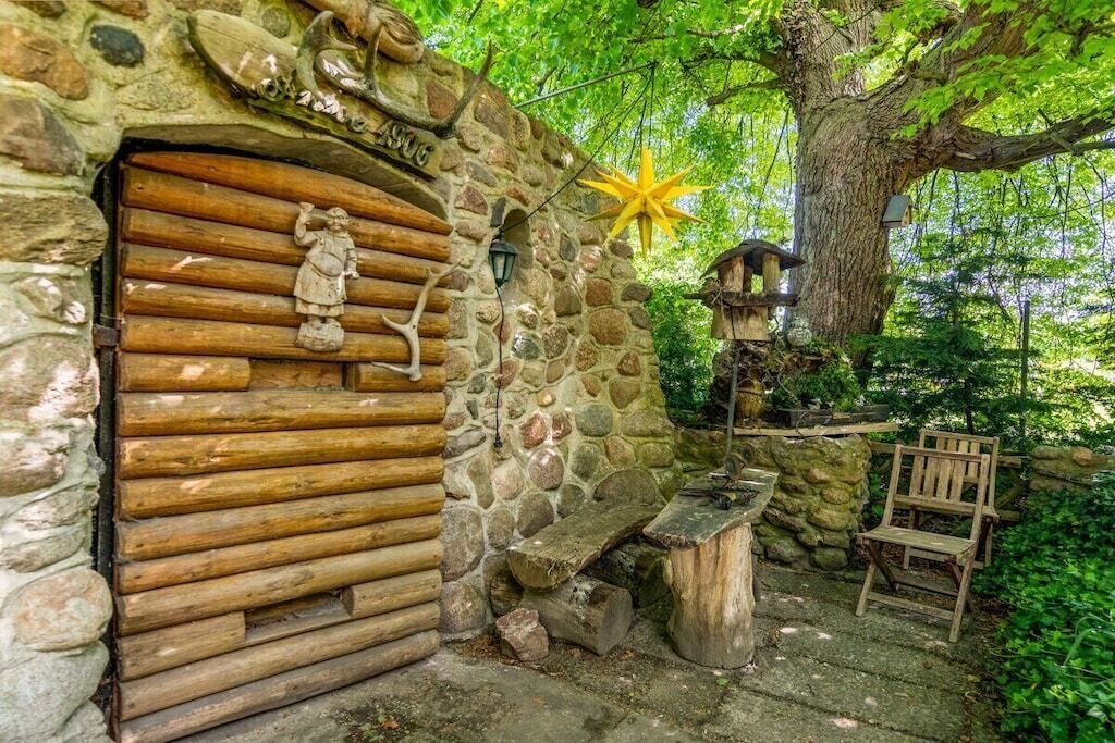 A rustic stone wall with a wooden door, a bench, and a wooden chair.