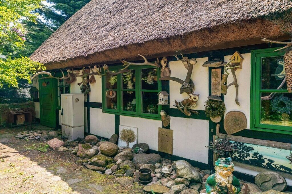 Un bâtiment rustique, doté d’un toit de chaume et orné de diverses cornes et bois de cervidés.