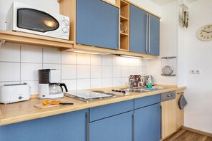 A modern kitchen with a microwave, toaster, coffee maker, and a sink. - 19 in the Granitz house (Binz)