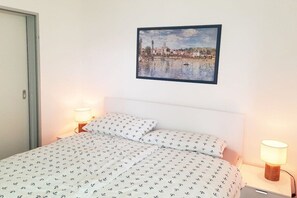 A hotel room with a bed, two bedside lamps, a wall-mounted painting, and a door. - 19 in the Granitz house (Binz)