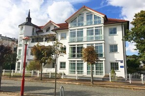 A white building with multiple windows and a red roof, surrounded by a white fence and trees. - 19 in the Granitz house (Binz)