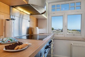 A modern kitchen with a stainless steel range, a toaster, and a view of the sea through large windows. - Holiday apartment in Binz with swimming pool (Binz)