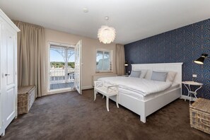 A bedroom with a bed, a chair, a small table, and a view through a glass door. - Holiday apartment in Binz with swimming pool (Binz)