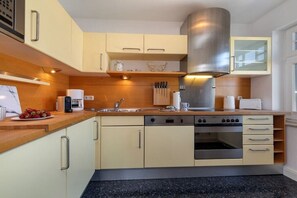 A modern kitchen with light-colored cabinets, stainless steel appliances, and a black granite countertop. - Holiday apartment in Binz with swimming pool (Binz)