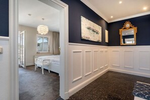 A bedroom with a bed, a chair, a dresser, a mirror, and a wall-mounted artwork. - Holiday apartment in Binz with swimming pool (Binz)