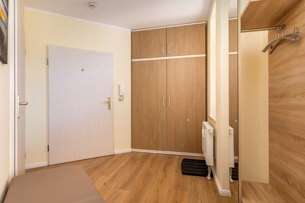 A room with a white door, wooden wardrobe, and a radiator.