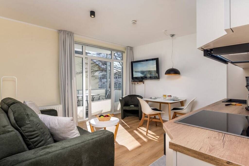 Een moderne woonkamer met een bank, een eettafel en een keuken met een fornuis.
