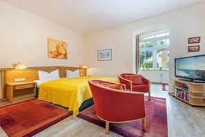 A hotel room with a bed, a TV, a bookshelf, and a window with a view. - Starfish in Villa Lucky (Binz)