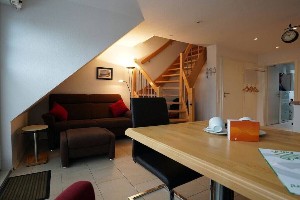 Un espace de vie compact comprenant un coin repas, un canapé, un escalier et un coin cuisine.