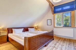 A bedroom with a wooden bed, a window with a view, and a radiator. - Garden house by the swan pond (Lassan)