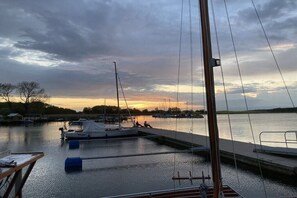 Un port de plaisance avec des bateaux amarrés, une eau calme et un coucher de soleil en arrière-plan.
