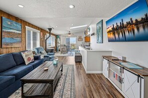 Una sala de estar moderna con un sofá, una mesa de centro y vistas de la ciudad a través de amplios ventanales.
