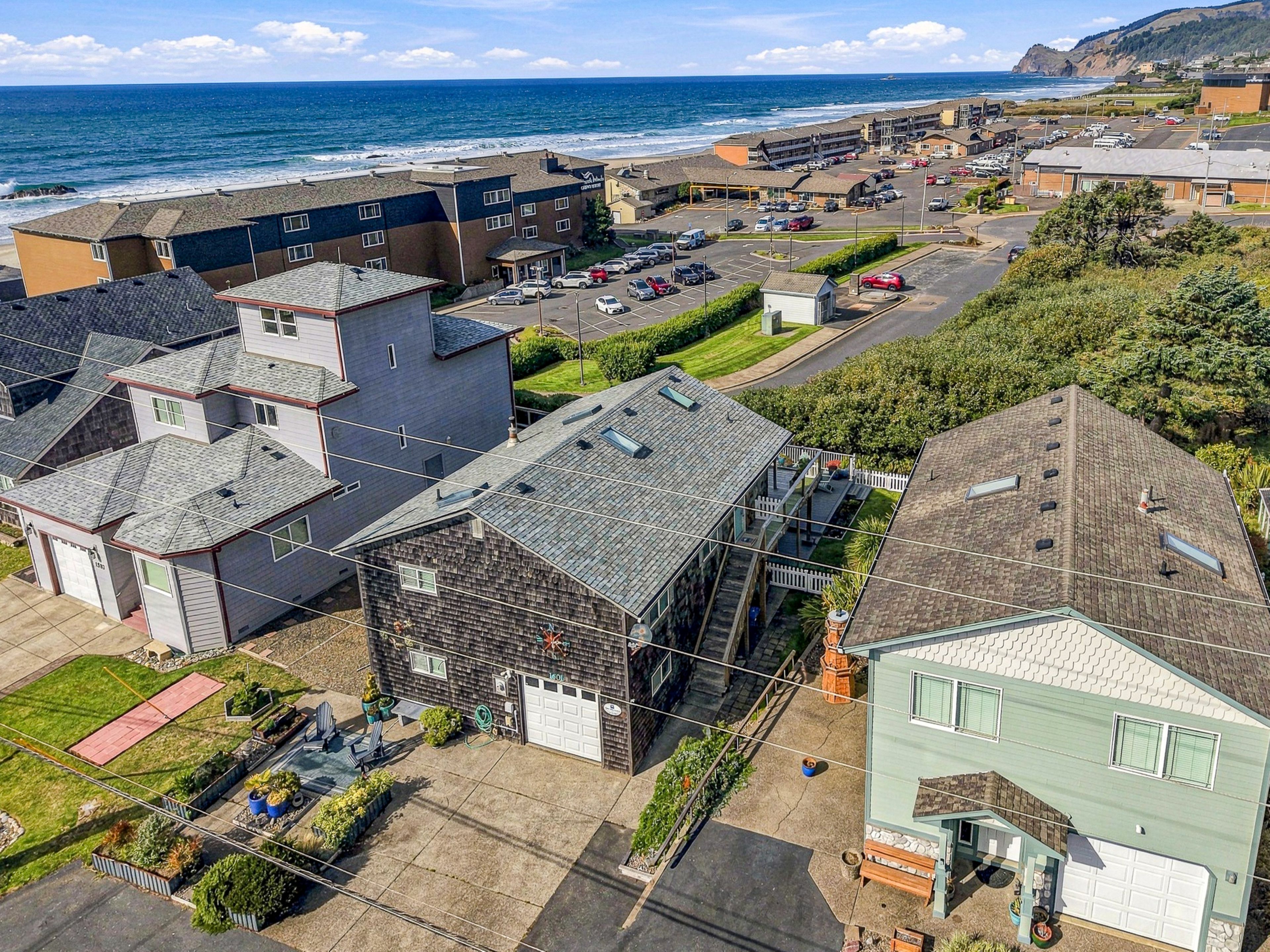 A coastal residential area with houses, a parking lot, and a view of the ocean.