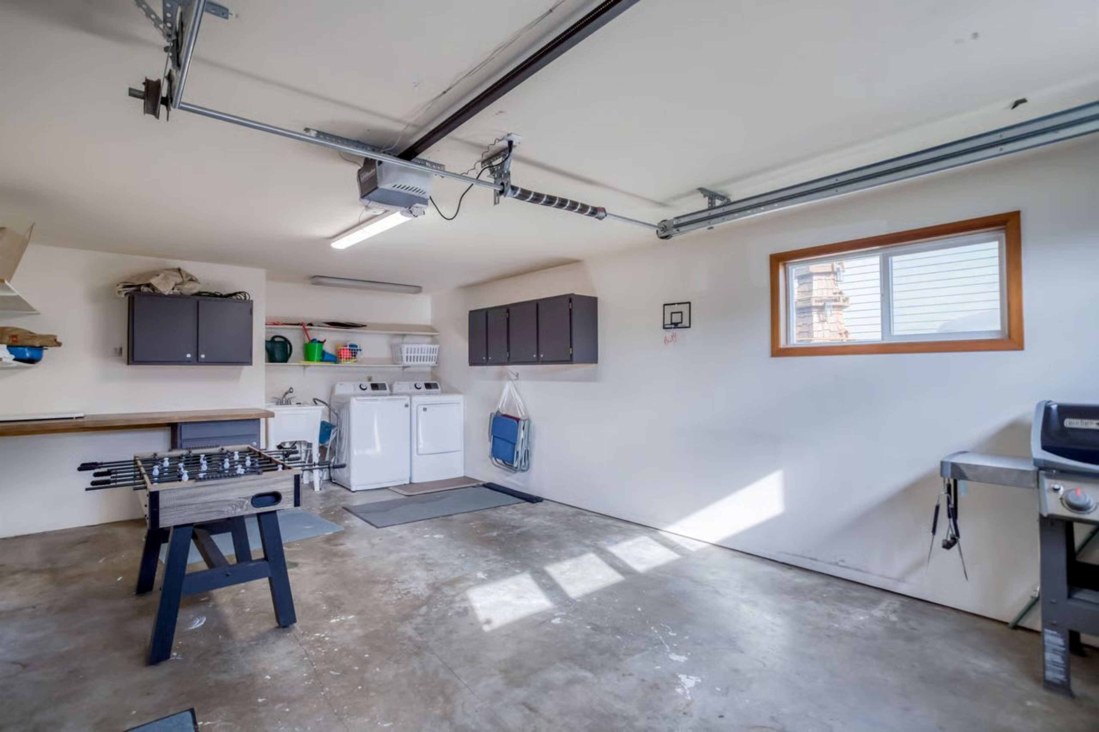 A laundry room with a washing machine, dryer, and a small table with a foosball table.