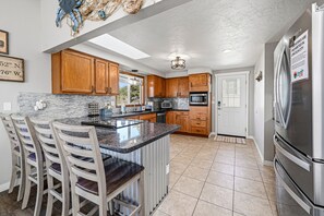 A modern kitchen with wooden cabinets, a granite countertop, and stainless steel appliances. - Lincoln City Amazing View Retreat: Hot Tub, Arcade Room, Steps to Beach (Lincoln City)
