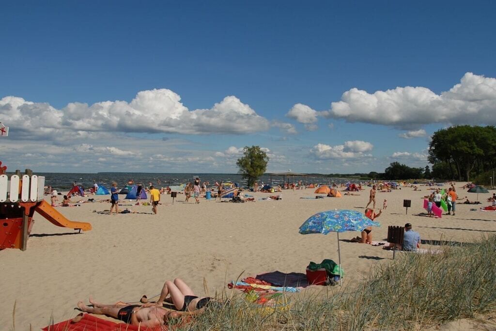 Une plage où l’on peut se détendre au soleil et se baigner, un terrain de jeux et des parasols de plage.