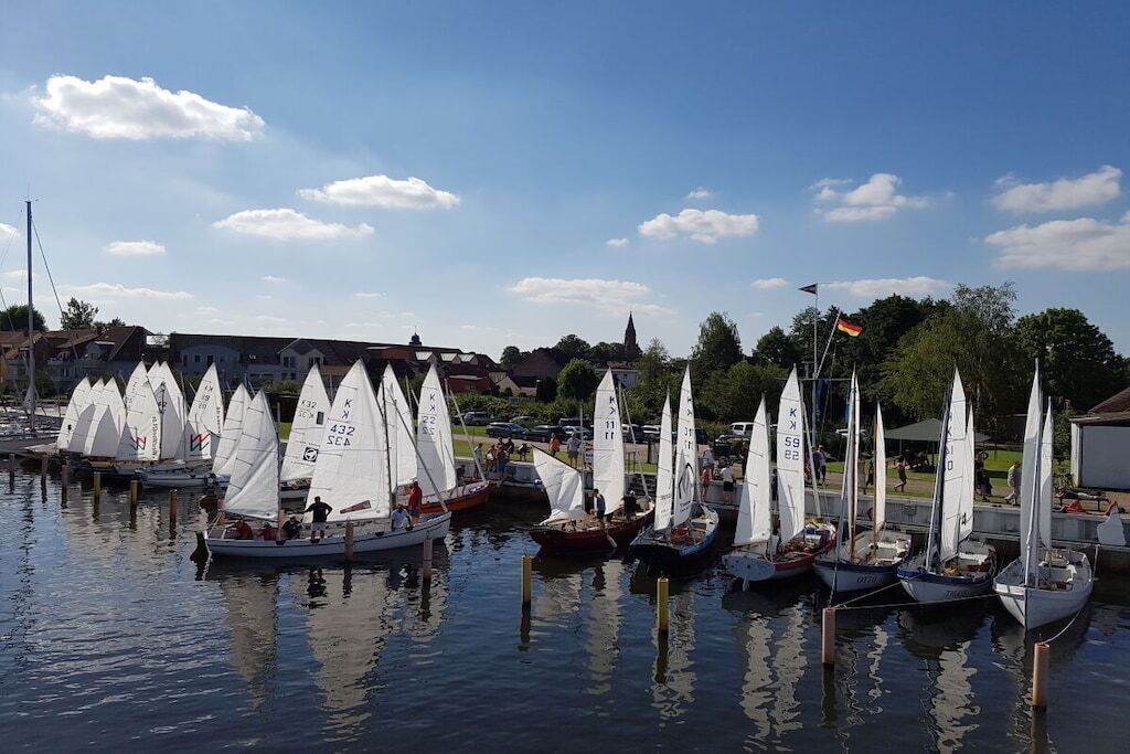 A marina with multiple sailboats docked at wooden piers.