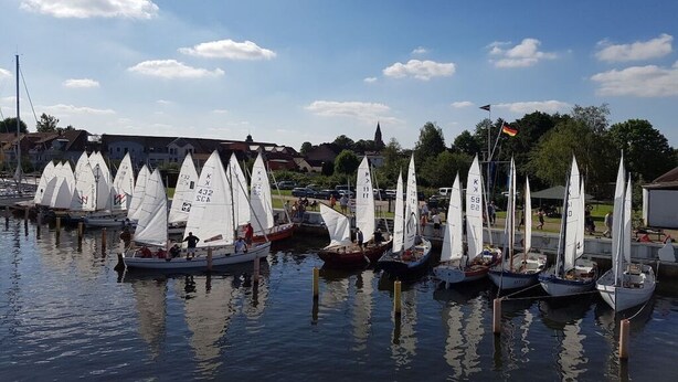 Un port esportiu amb diversos velers amarrats a molls de fusta.