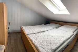 Ein Einzelbett in einem Zimmer mit schräger Decke und einem Oberlicht.