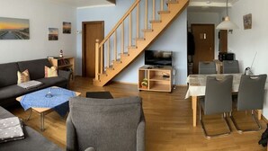Sala de estar com sofá, mesa de centro e um espaço de refeições com cadeiras e mesa.
