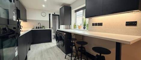 A modern kitchen with a central island, bar stools, and a large window.