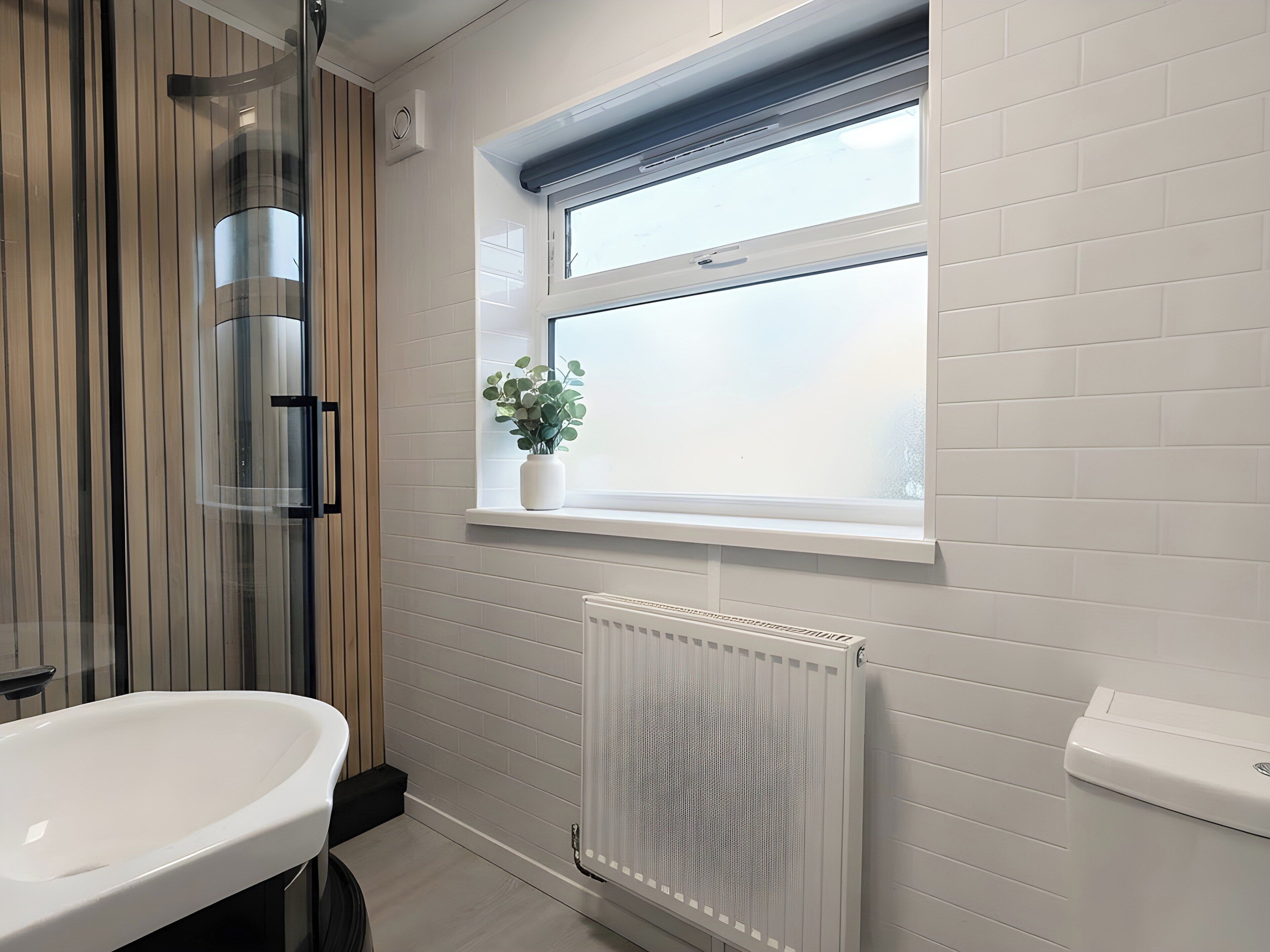 A bathroom with a freestanding bathtub, a window with a plant, and a white radiator.
