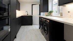 A modern kitchen with built-in appliances, a central island, and a window providing natural light. - House Sleeps 6 With Patio (Cardiff)