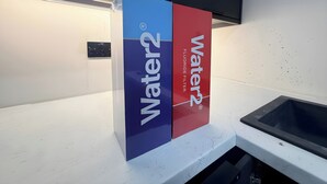 A kitchen counter with a water filter dispenser and a sink. - House Sleeps 6 With Patio (Cardiff)