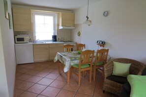 A compact kitchen with a dining table and chairs, a microwave, and a radio. - 2 on the Grafel farm (Kirchlinteln-Stemmen)