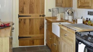 A kitchen with wooden cabinets, a white countertop, a stove, and a door with a black handle.