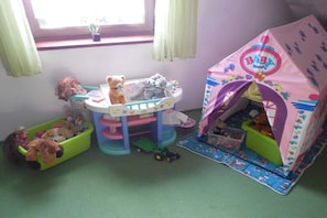 Un espace de jeux pour enfants avec une petite table, une voiture jouet et une tente de jeu.