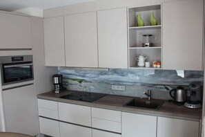A modern kitchen with a marble backsplash, built-in oven, and a coffee maker on the countertop. - 10 in the Palais am Meer II (Cuxhaven-Duhnen)